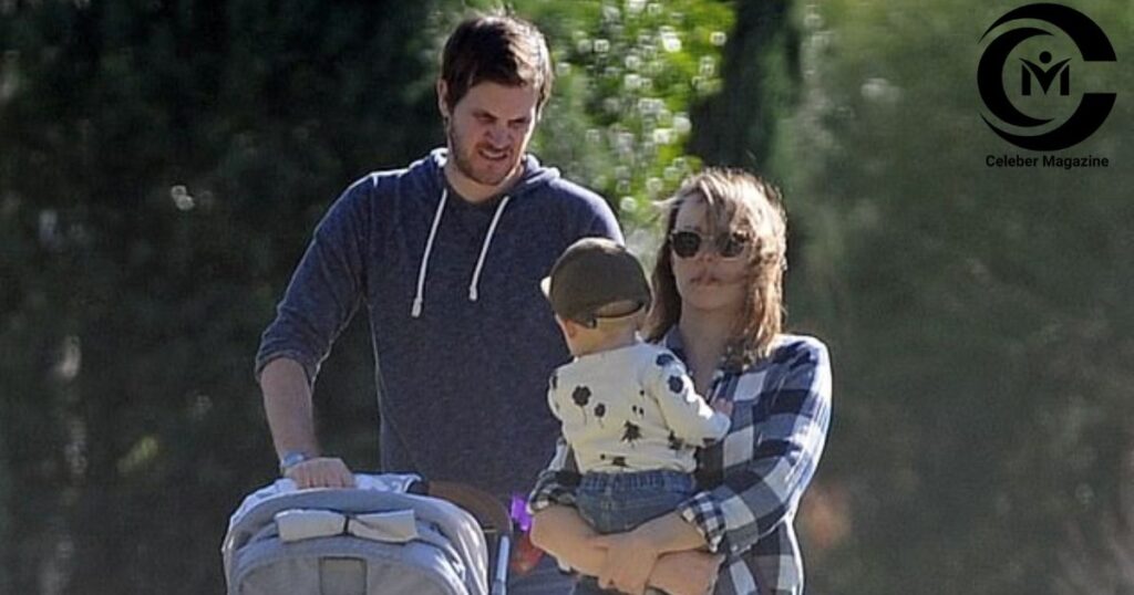 Rachel McAdams walking with partner and child outdoors.